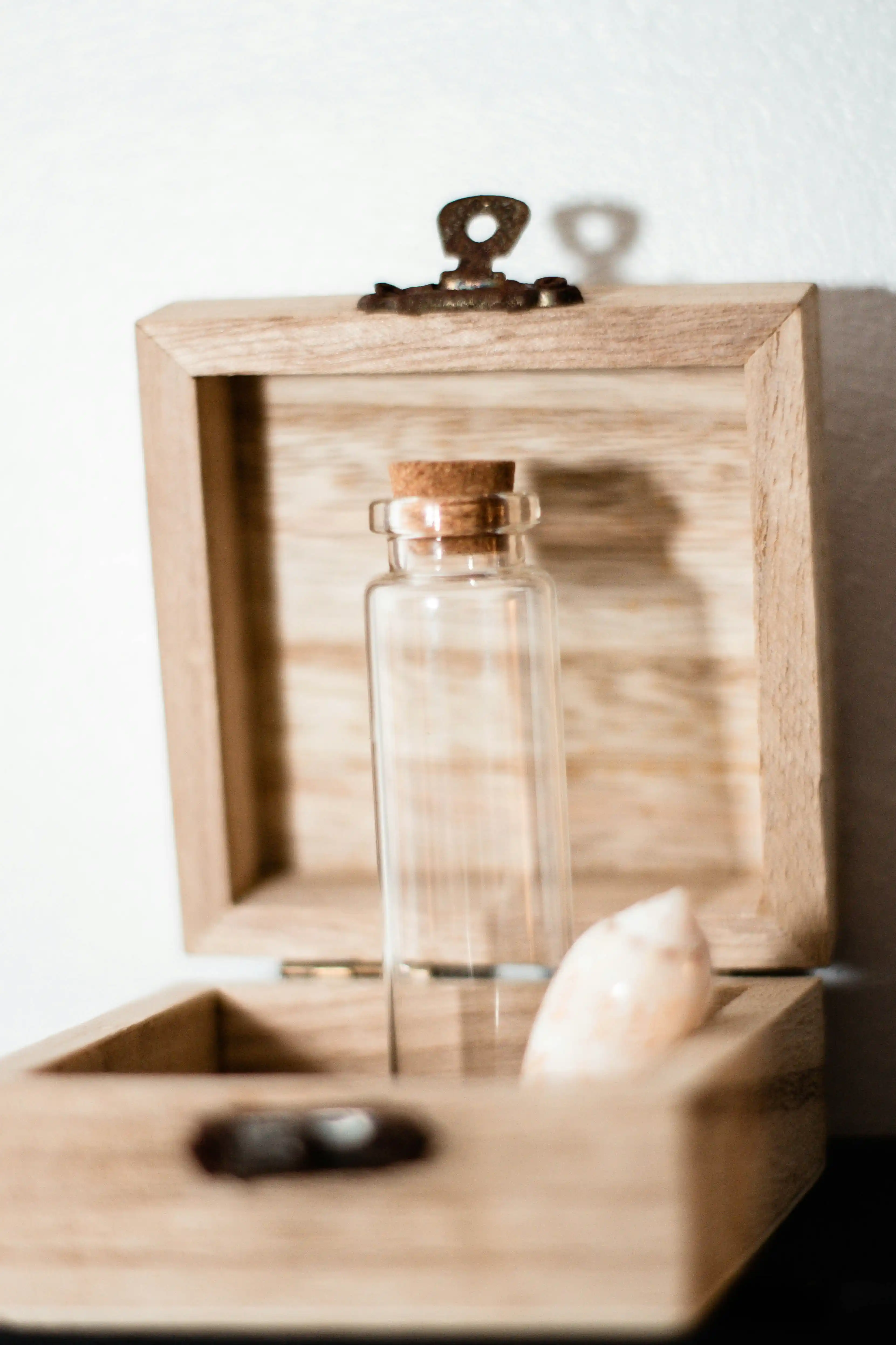 An empty clear glass jar sitting on a wooden shelf, used to hold a small keepsake
